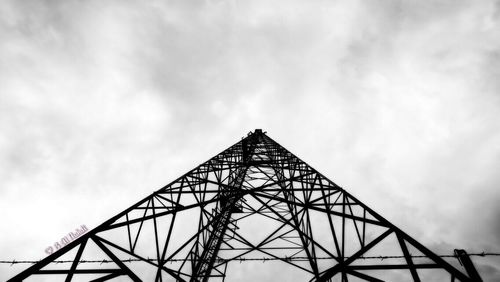 Low angle view of metal structure against cloudy sky