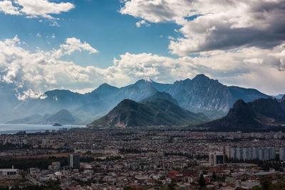 Aerial view of townscape by mountains against sky