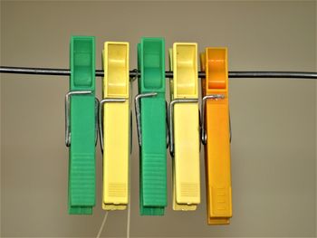 Close-up of multi colored clothespins on table against wall