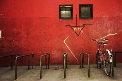 Bicycle parked against red wall