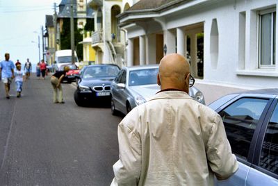 Rear view of man with umbrella on street in city