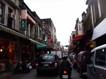 Cars on street in city against clear sky