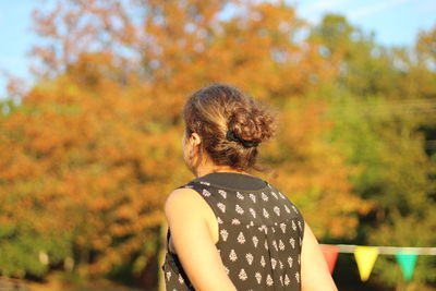 Rear view of woman standing against trees