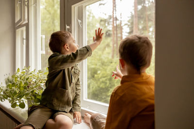 Children sitting on windowsill and waiting for someone coming. two brothers, friends. 