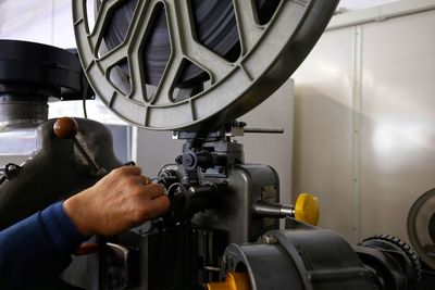 Cropped hand of male mechanic repairing with film projector