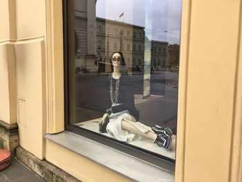 Reflection of man sitting in glass building