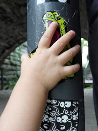 Cropped image of kid hand on pole