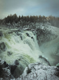 Scenic view of waterfall against sky during winter