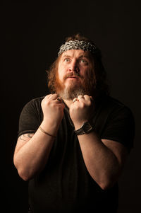 Portrait of mature man standing against black background