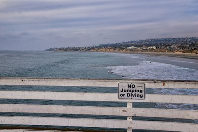 Information sign on beach against sky