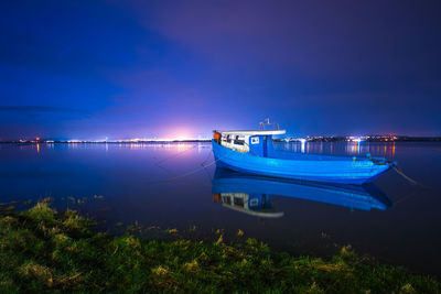 Boat moored on sea against sky at night