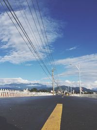 Electricity pylon by road against sky