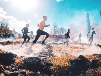 Men jumping in water against sky