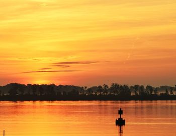 Scenic view of lake against trees and sky during sunset