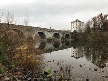 Arch bridge over river against sky