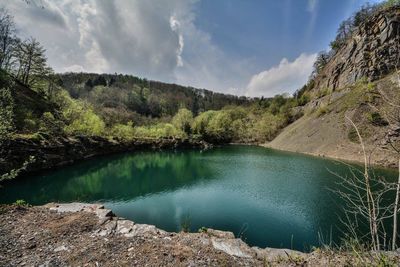 Scenic view of river by mountains against sky