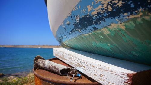 Close-up of rusty boat moored at beach against sky
