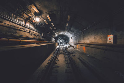 Railroad tracks in illuminated tunnel