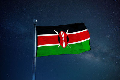 Low angle view of kenyan flag against star field sky