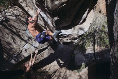 Shirtless man climbing rock