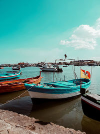 Boats moored on shore against blue sky