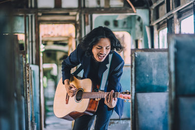 Young guitarist playing guitar in bus