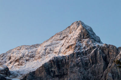 Low angle view of rocky mountain against clear sky