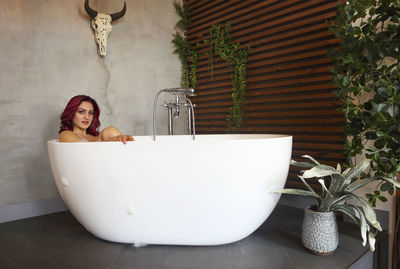 Portrait of young woman sitting in bathtub