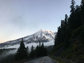 Road by mountains against clear sky during winter