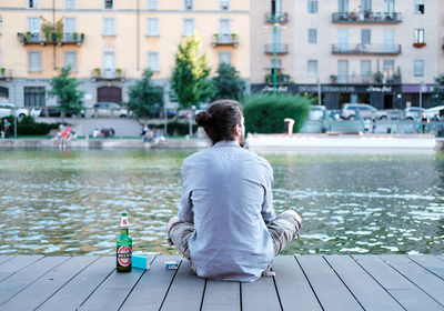 Rear view of man sitting by lake