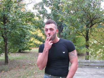 Portrait of young man standing against trees