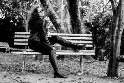 Full length of fashionable teenage girl sitting on park bench