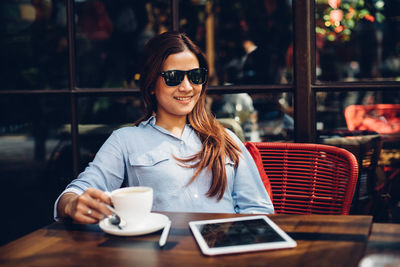 Young woman wearing sunglasses while having coffee at restaurant