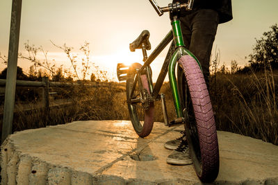 Low section of man cycling in bicycle at sunset