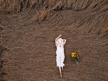 Aerial view of a pretty young woman enjoying the outdoors. girl wearing a white dress lying in wheat