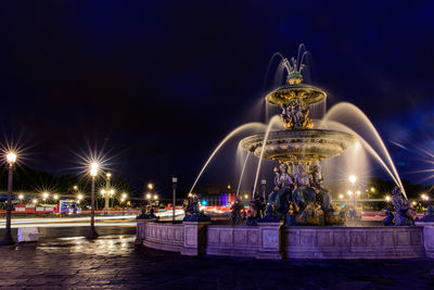 Illuminated fountain against blue sky at night