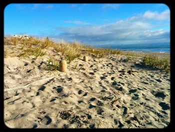 Scenic view of beach against cloudy sky