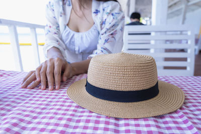 Straw hat against blurred woman background on chair of restaurant beside beach. summer vacation s