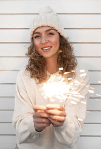 Portrait of young girl holding sparkler outdoors