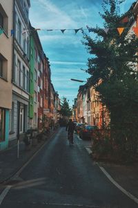 Rear view of man walking on road along buildings