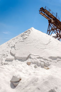 Heap of salt by machinery against blue sky