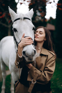 Portrait of young woman with horse on field