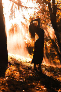 Silhouette woman standing on field against trees