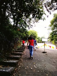 Rear view of men walking on road against trees