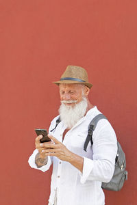 Man holding umbrella standing against red wall