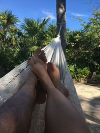 Low section of couple relaxing in hammock at beach