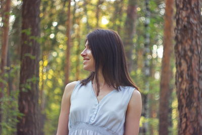 Mid adult woman standing against trees in forest
