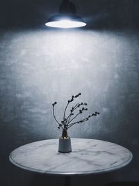 Illuminated lamp on table against wall at home