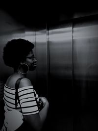 Side view of young woman looking away while standing in elevator