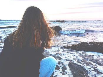 Rear view of woman on beach against sky